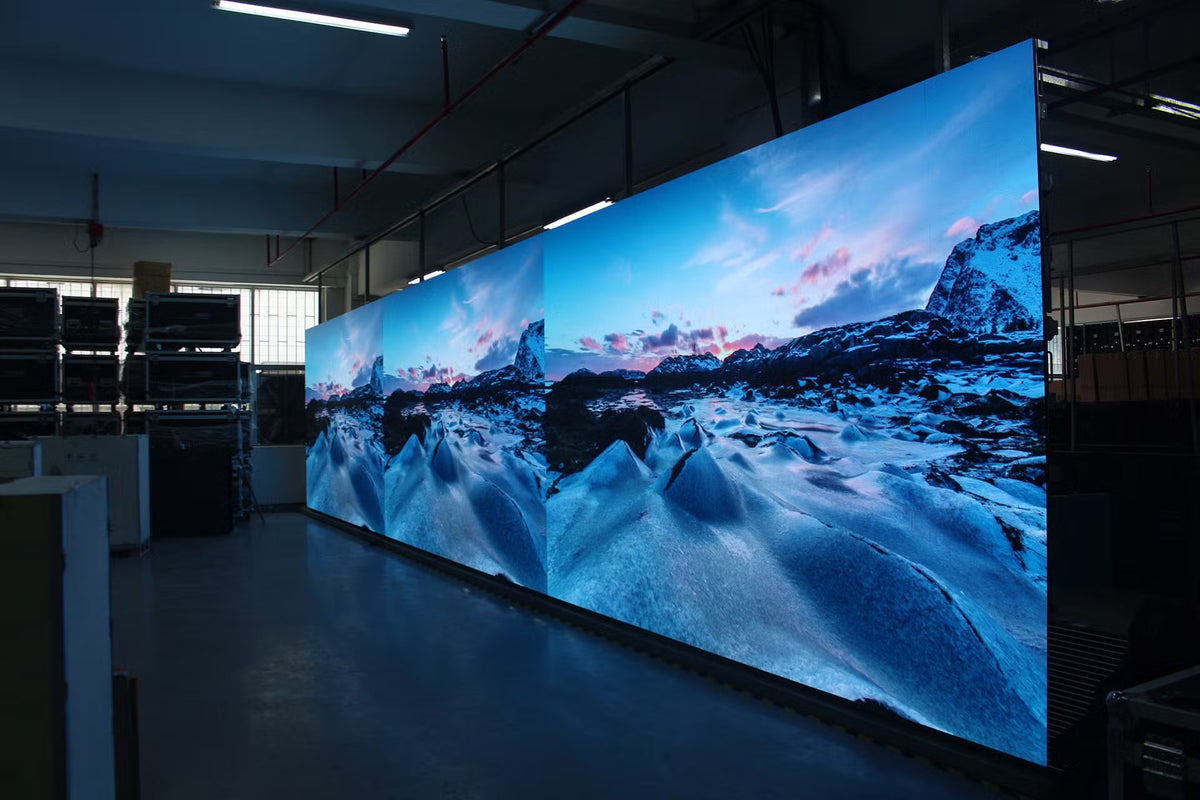 alt tekst indoor led display  00:24 Grote indoor LED-videowall met helder berglandschap in professionele installatieruimte.